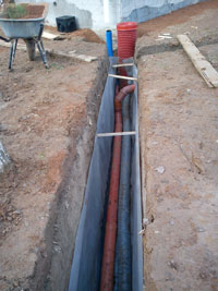 Подготовка к засыпке дренажной и канализационной трубы используемой для отвода воды с кровли при помощи дождеприемника